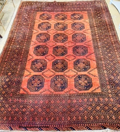 An Afghan pale red ground carpet. 350x280cm.